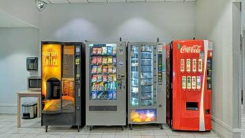 Een rij automaten met diverse snacks en drankjes, waaronder een Coca-Cola automaat.