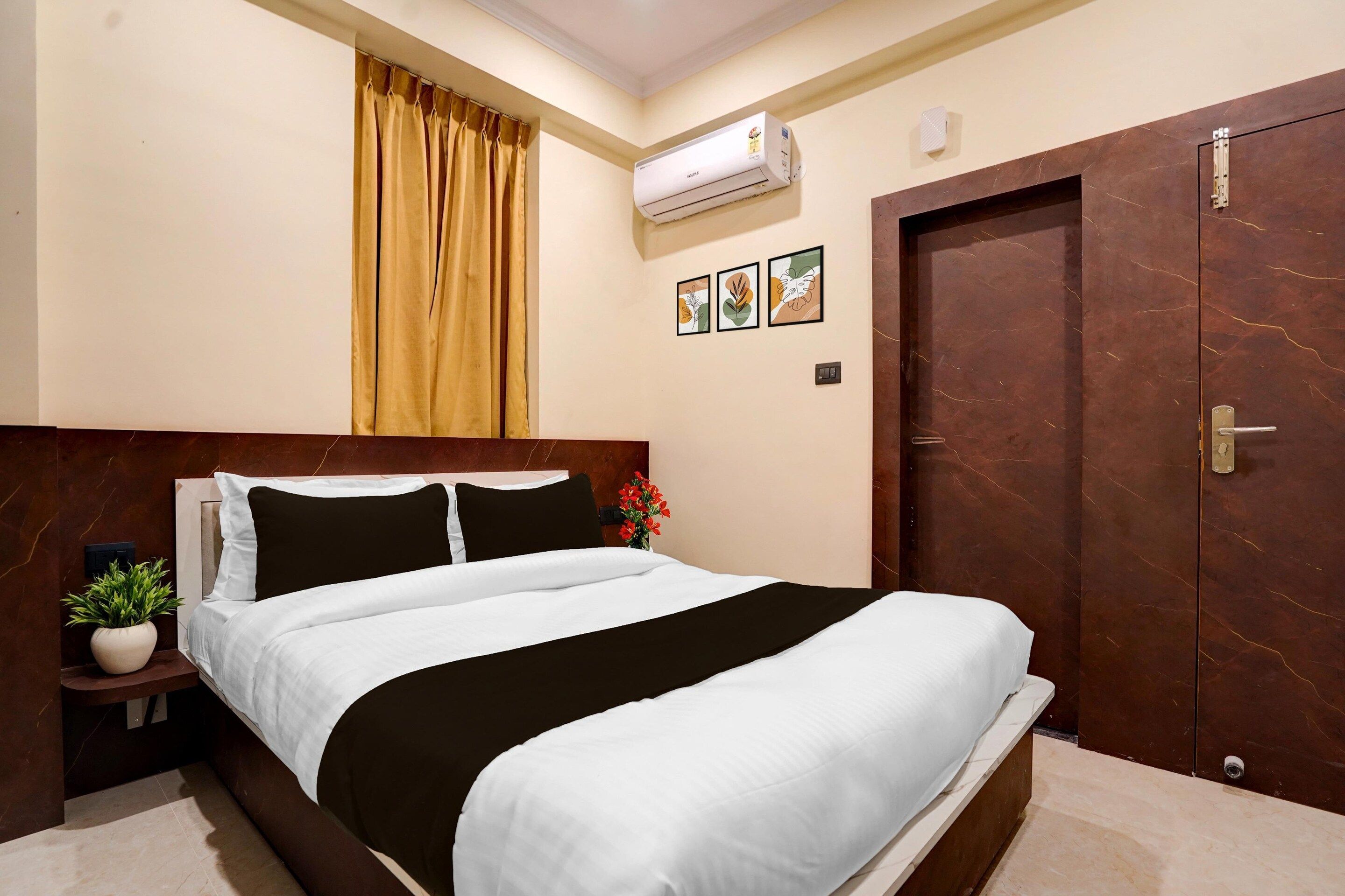 Ein Hotelzimmer mit Bett, Klimaanlage, Tür und einem an der Wand hängenden Bild.