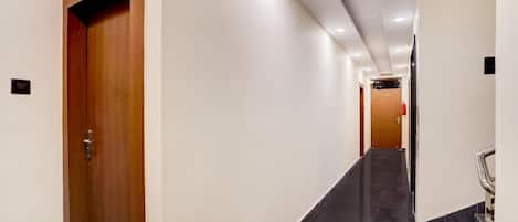 A hallway with a wooden door marked '203', a black tiled floor, and a handrail on the right.