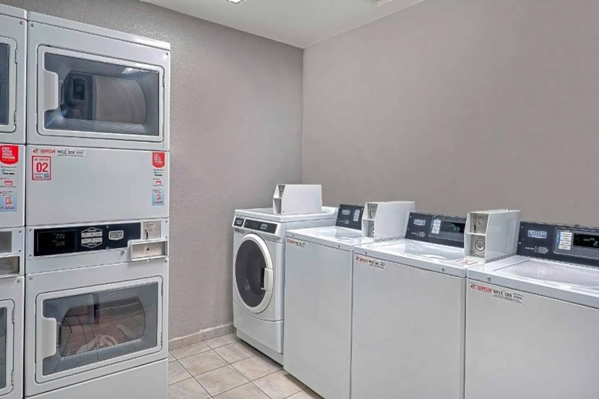 A laundry facility with stacked washers and dryers, a washing machine, and a drying machine.