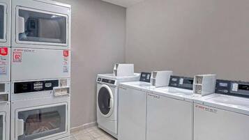 A laundry facility with stacked washers and dryers, a washing machine, and a drying machine.