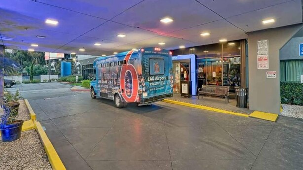 Um ônibus estacionado em um terminal com uma placa indicando destino: Aeroporto de LAX.