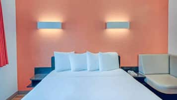 A hotel room with a bed, a nightstand, a chair, and two wall-mounted lights.