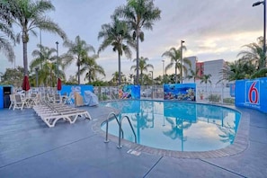 An outdoor swimming pool with lounge chairs, palm trees, and a mural on the wall. - 1 King Bed|Mini Fridge (Inglewood)