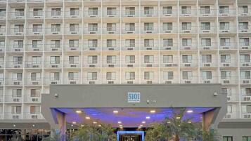Een hotel met meerdere verdiepingen, een gelijkmatige gevel, nummer 5101, en een centrale ingang met een blauw verlichte luifel.