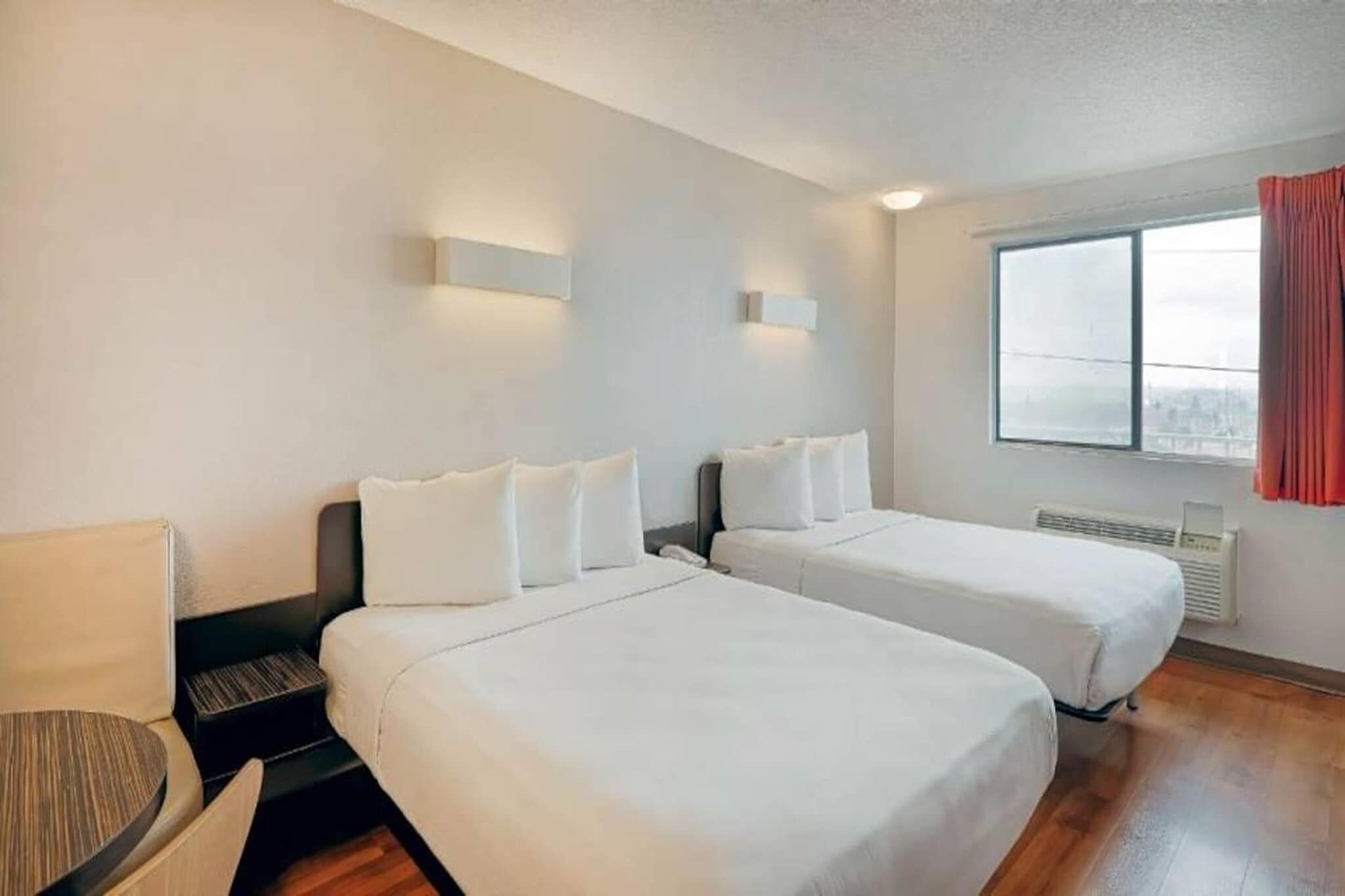 Een hotelkamer met twee bedden, een bureau, een stoel en een raam met uitzicht.
