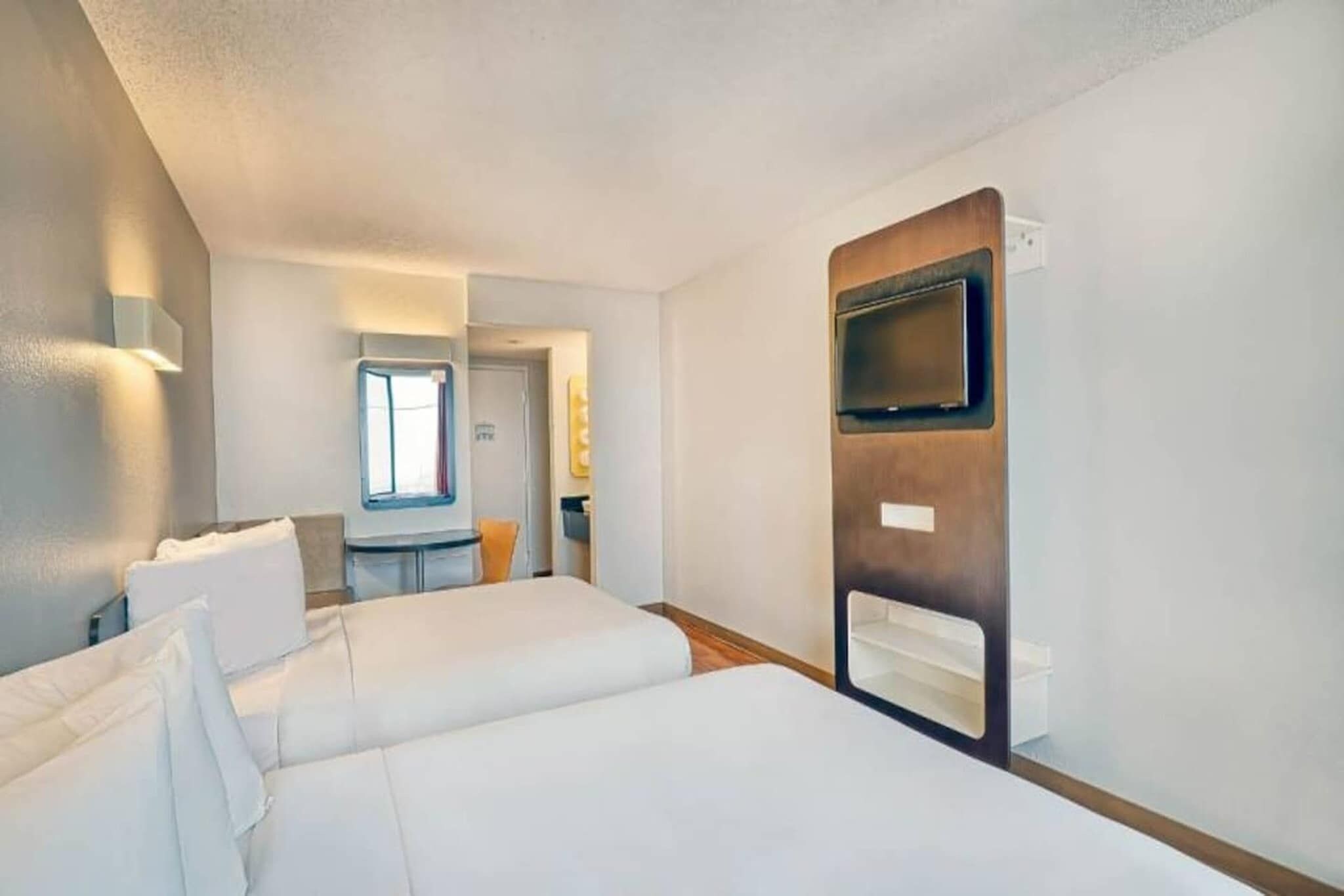 Ett hotellrum med två sängar, en TV och ett litet bord med en stol.
