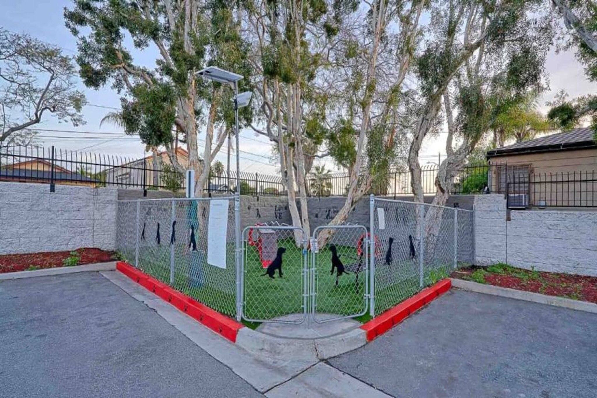 Un'area recintata con vialetto lastricato, alberi e un edificio sullo sfondo.