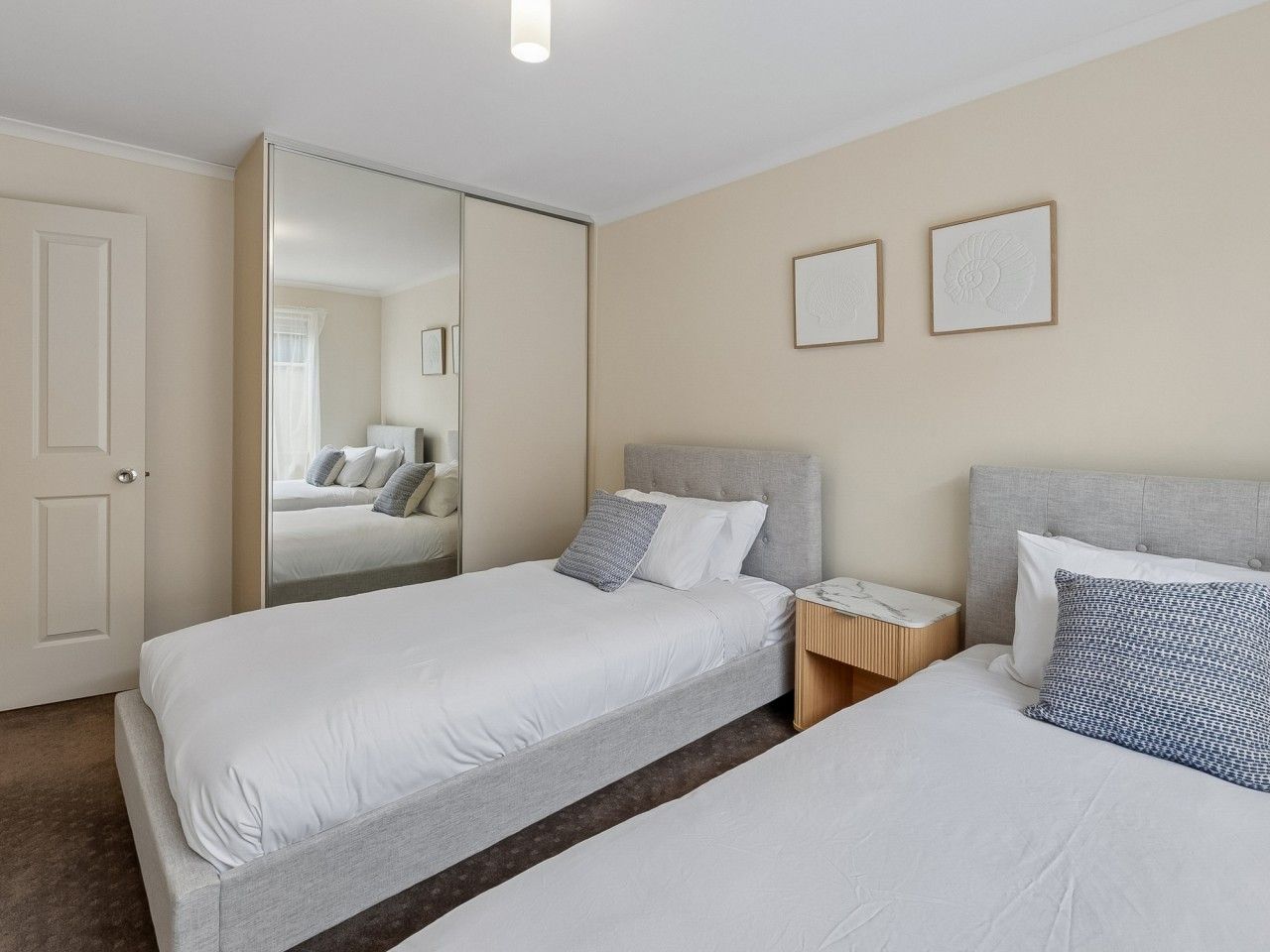 Une chambre d’hôtel avec deux lits, un miroir et une table de chevet.