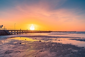 Eine Pier, die sich in ein Gewässer erstreckt, während die Sonne untergeht.