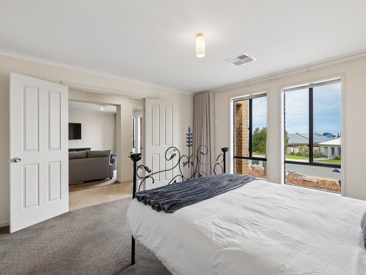A bedroom with a bed, a sofa, and a view of the outside.