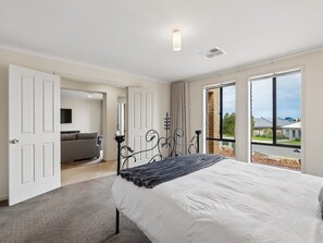 Ein Schlafzimmer mit Bett, einer Couch und Blick ins Freie.