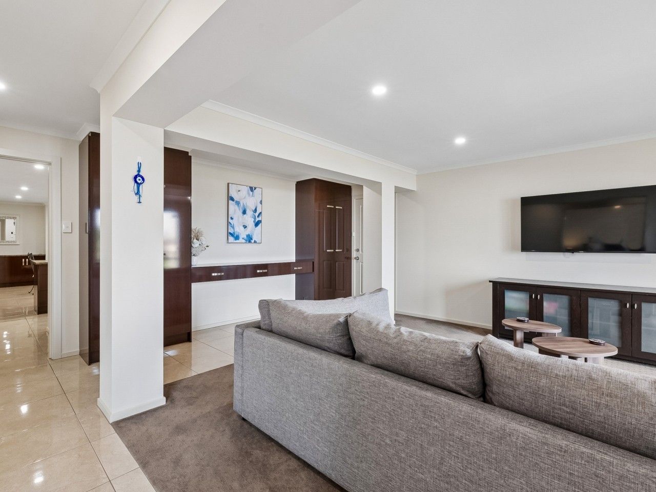 Een moderne woonkamer met een grijze bank, een flatscreen televisie en een houten kast.