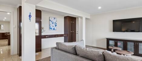 Een moderne woonkamer met een grijze bank, een flatscreen televisie en een houten kast.