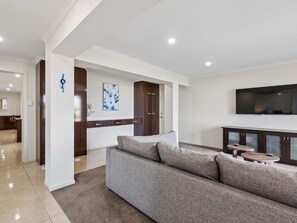 Ein modernes Wohnzimmer mit einem grauen Sofa, einem Flachbildfernseher und einem Holzschrank.