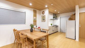 A modern kitchen with a wooden table and chairs, a stove, and a refrigerator.