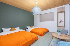 A room with two beds, a round table, and a chair. - Nikyo Tangerine Soraniwa Villa Osaka (Osaka)