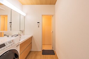 A compact bathroom with a washing machine, a sink, and a mirror. - Nikyo Tangerine Soraniwa Villa Osaka (Osaka)