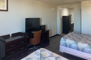 A hotel room with a desk, a television, a microwave, a wardrobe, and two beds with patterned bedding. - 2 Queen Beds|Nsmk,Kitchen (Borger TX)