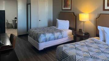 A hotel room with two beds, a desk, and a chair.
