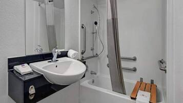 Un baño con lavamanos, espejo, ducha y toallero.