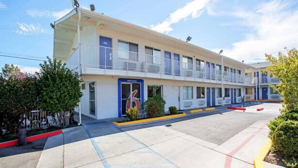 A motel with a two-story structure, a blue entrance, and a 'Welcome' sign. - 1 Queen Bed | Prescott (Prescott)