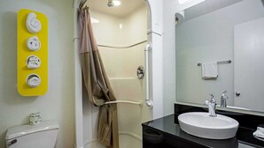 A bathroom with a toilet, a sink, a shower with a curtain, and a towel rack with towels. - 1 Queen Bed | Prescott (Prescott)