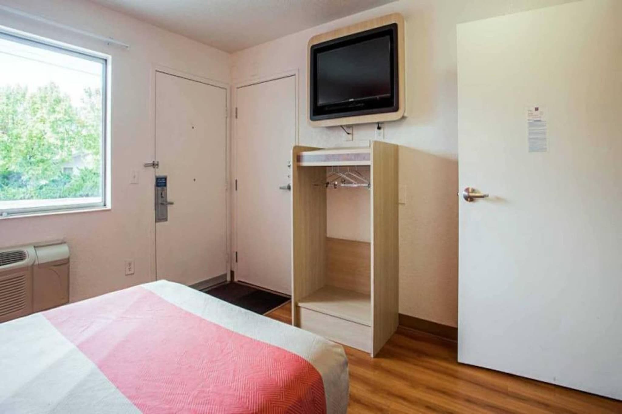 Ein Schlafzimmer mit Bett, Kleiderschrank, Fernseher und Fenster.