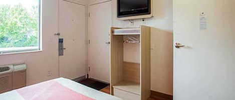 A bedroom with a bed, a wardrobe, a television, and a window.