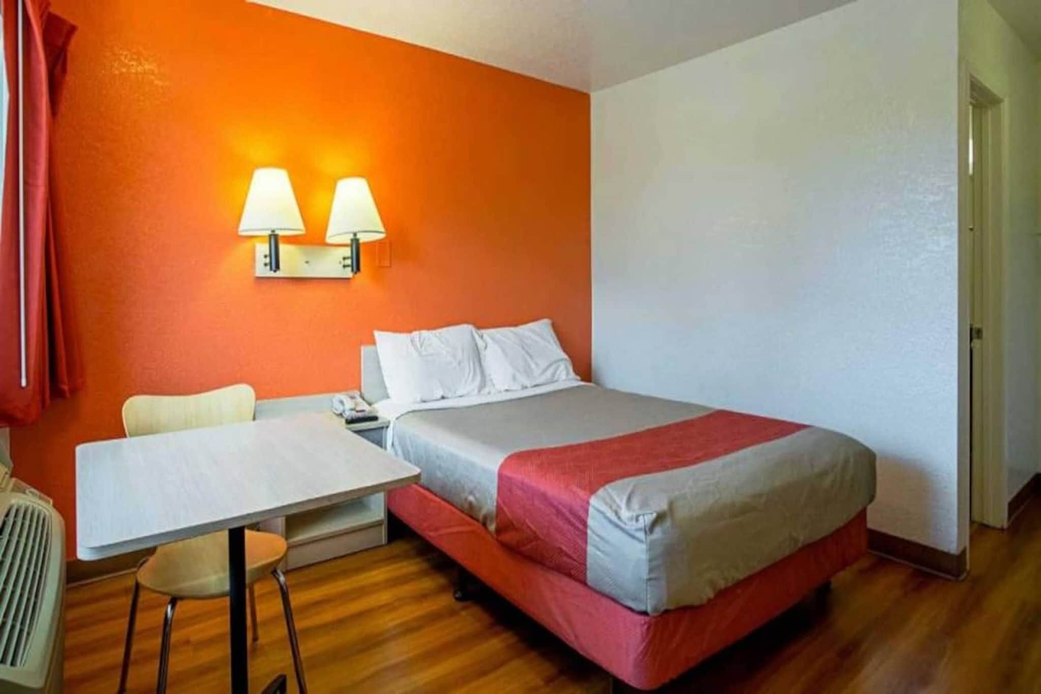 Une chambre d’hôtel avec un lit, une table, deux chaises et une lampe.