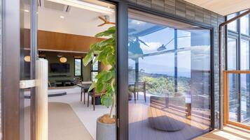 A modern interior with a dining area, a large potted plant, and a view through a glass door.