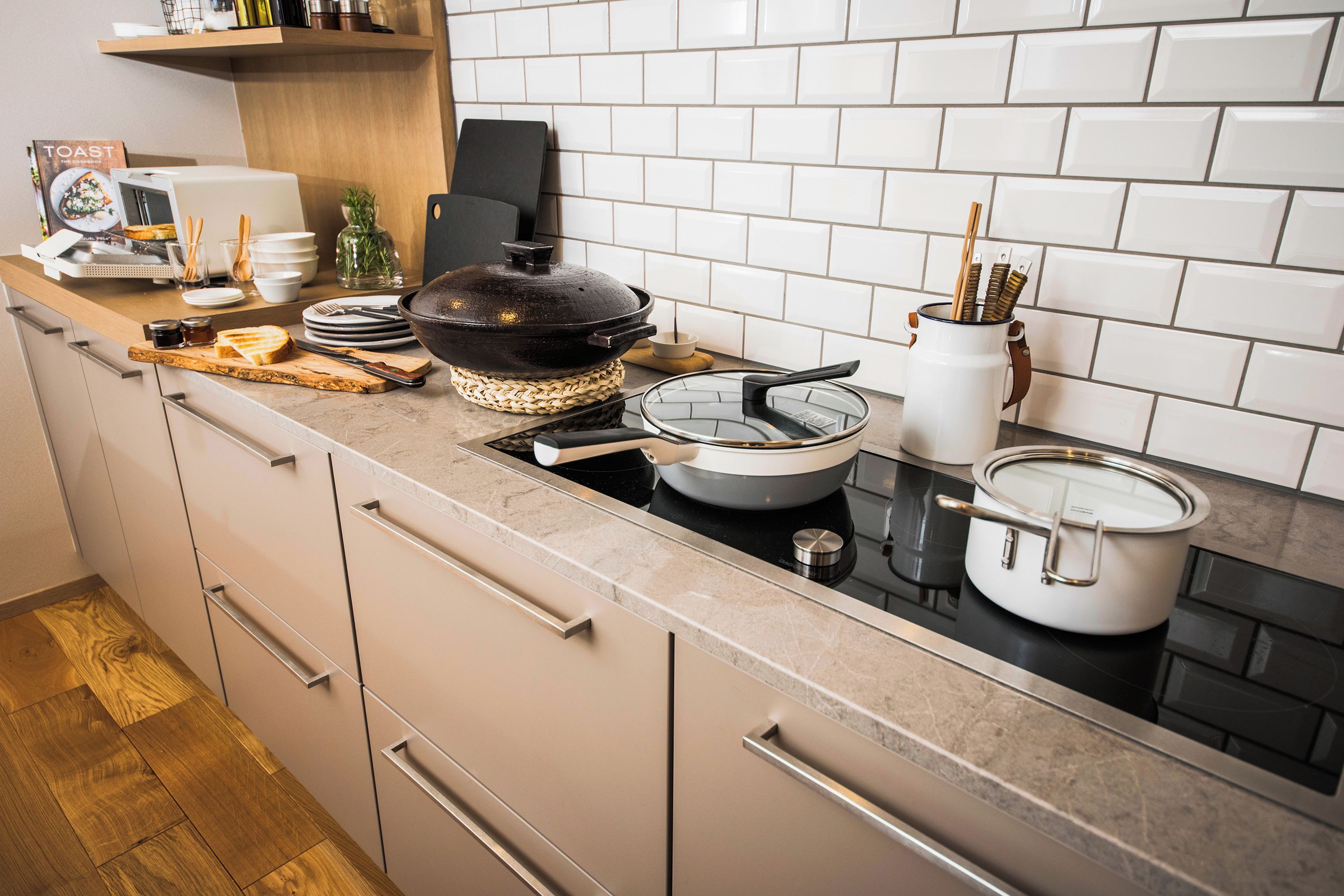 Una cocina moderna con estufa, distintos utensilios de cocina y un libro de recetas en la encimera.