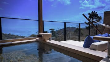 A spa area with a view of the sea, a wooden bench, and a small wooden structure.