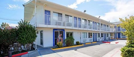 A motel with a two-story structure, a blue entrance, and a 'Welcome' sign.