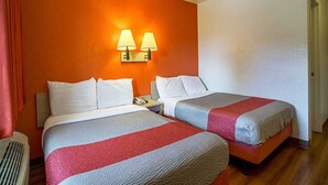 Ein Hotelzimmer mit zwei Betten, einem Nachttisch, einem Telefon und zwei Wandlampen.