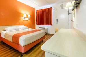 A hotel room with a bed, a desk, an air conditioning unit, and a window with curtains. - 1 Queen Bed | Phoenix Airport (Tempe)