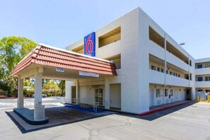 Un motel de varios pisos con una zona de estacionamiento cubierta y un cartel que indica el número de habitaciones.