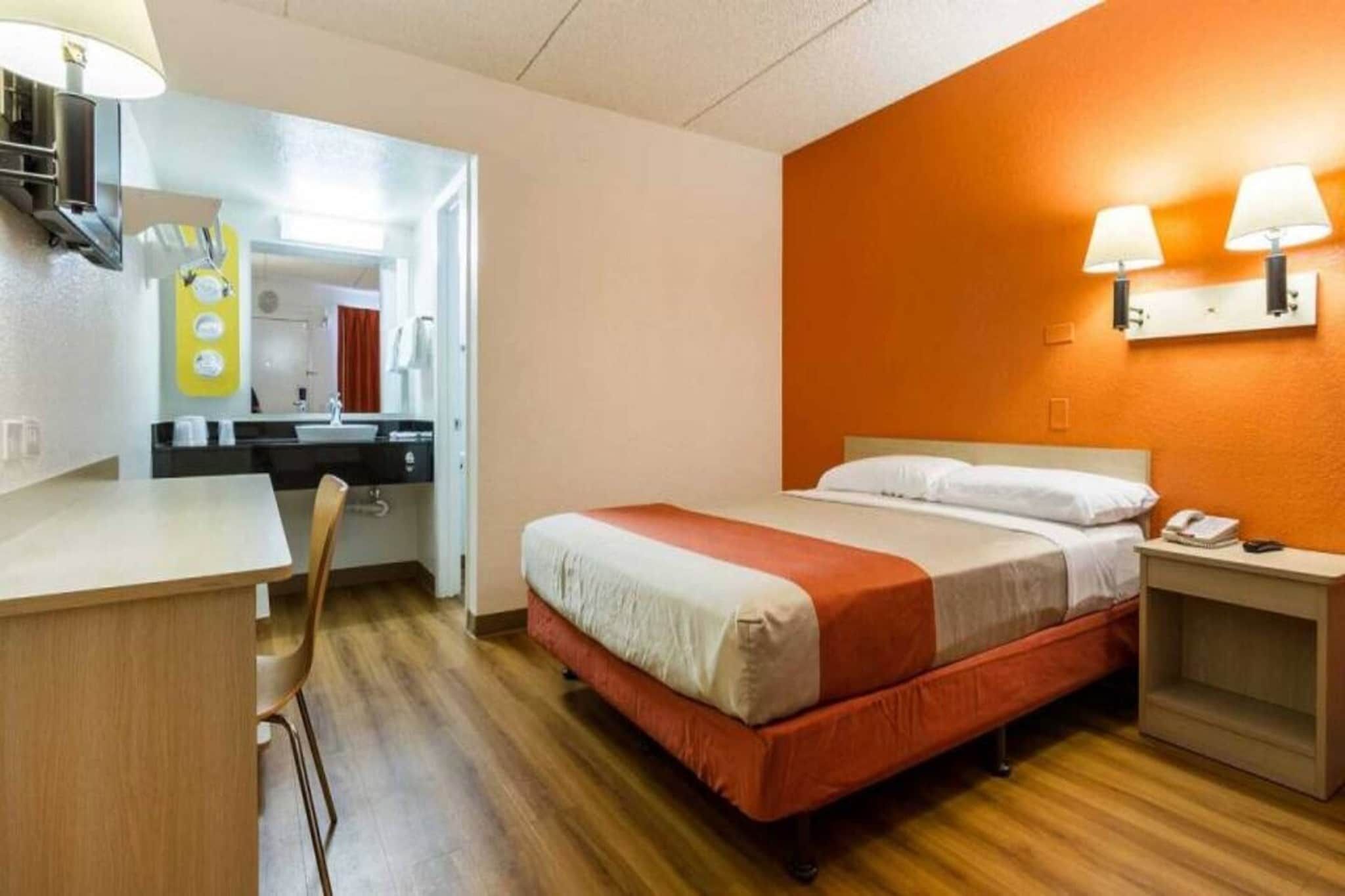 Una habitación de hotel con una cama, mesita de noche y escritorio con silla.