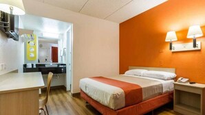 Ein Hotelzimmer mit einem Bett, einem Nachttisch und einem Schreibtisch mit Stuhl.