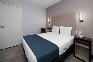Ein Hotelzimmer mit Bett, Nachttischen und einer Tür.