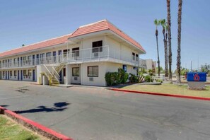 Un motel à deux étages avec un toit rouge, un espace de stationnement couvert et un panneau indiquant le numéro 6.