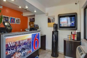 Un comptoir d’accueil de motel avec une grande pancarte indiquant : « Nous laisserons la lumière allumée pour vous. »