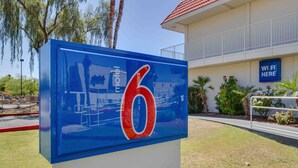 Schild eines Motels mit der Nummer 6, ein Gebäude mit rotem Dach und ein Hinweis auf WLAN.