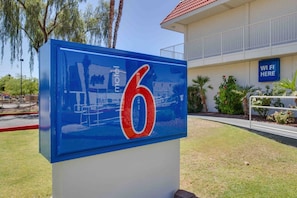 Señal de motel con el número 6, un edificio de techo rojo e indicación de disponibilidad de WiFi.