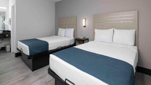Ein Hotelzimmer mit zwei Betten, einem kleinen Tisch, einem Nachttisch und einem Spiegel.