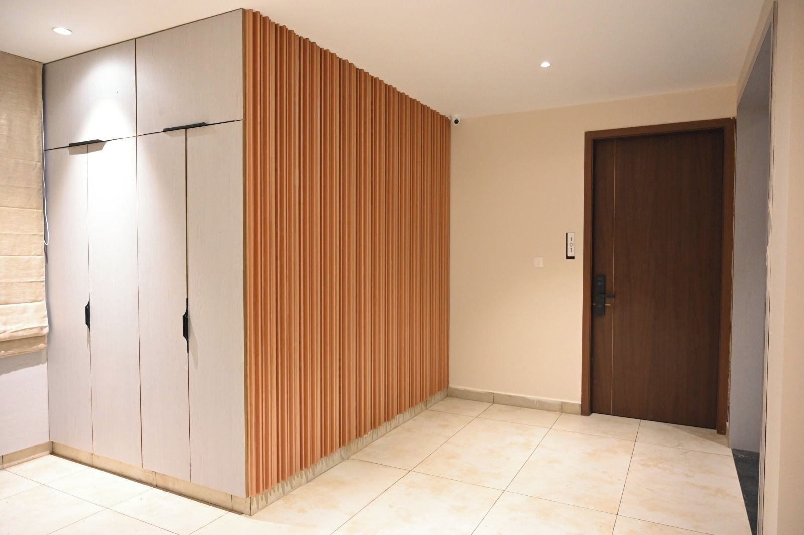 Une pièce dotée d’une armoire, d’un mur recouvert de panneaux en bois, d’une porte et d’un revêtement de sol carrelé.