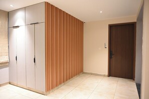 A room with a wardrobe, a wooden panel wall, a door, and tiled flooring. - LE PRESTIGE RESIDENCY Tindivanam (Tindivanam)