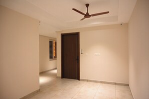 Un pasillo con ventilador de techo, una puerta y un ventanal con persianas.