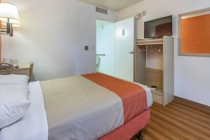 Une chambre d’hôtel comprenant un lit, un bureau avec un téléphone, une armoire et un téléviseur.