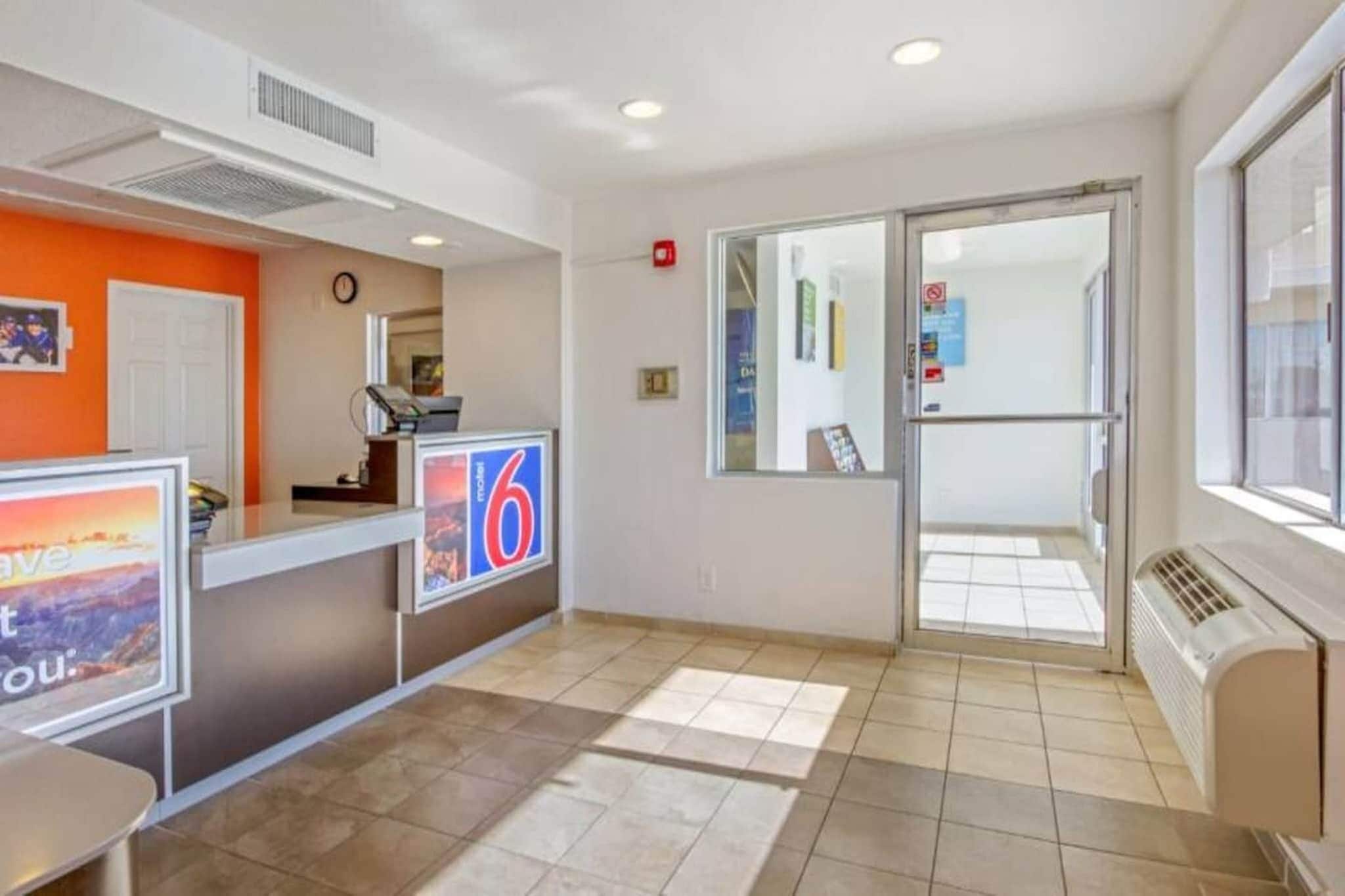 A reception area with a counter, a clock, and a door leading to a balcony.